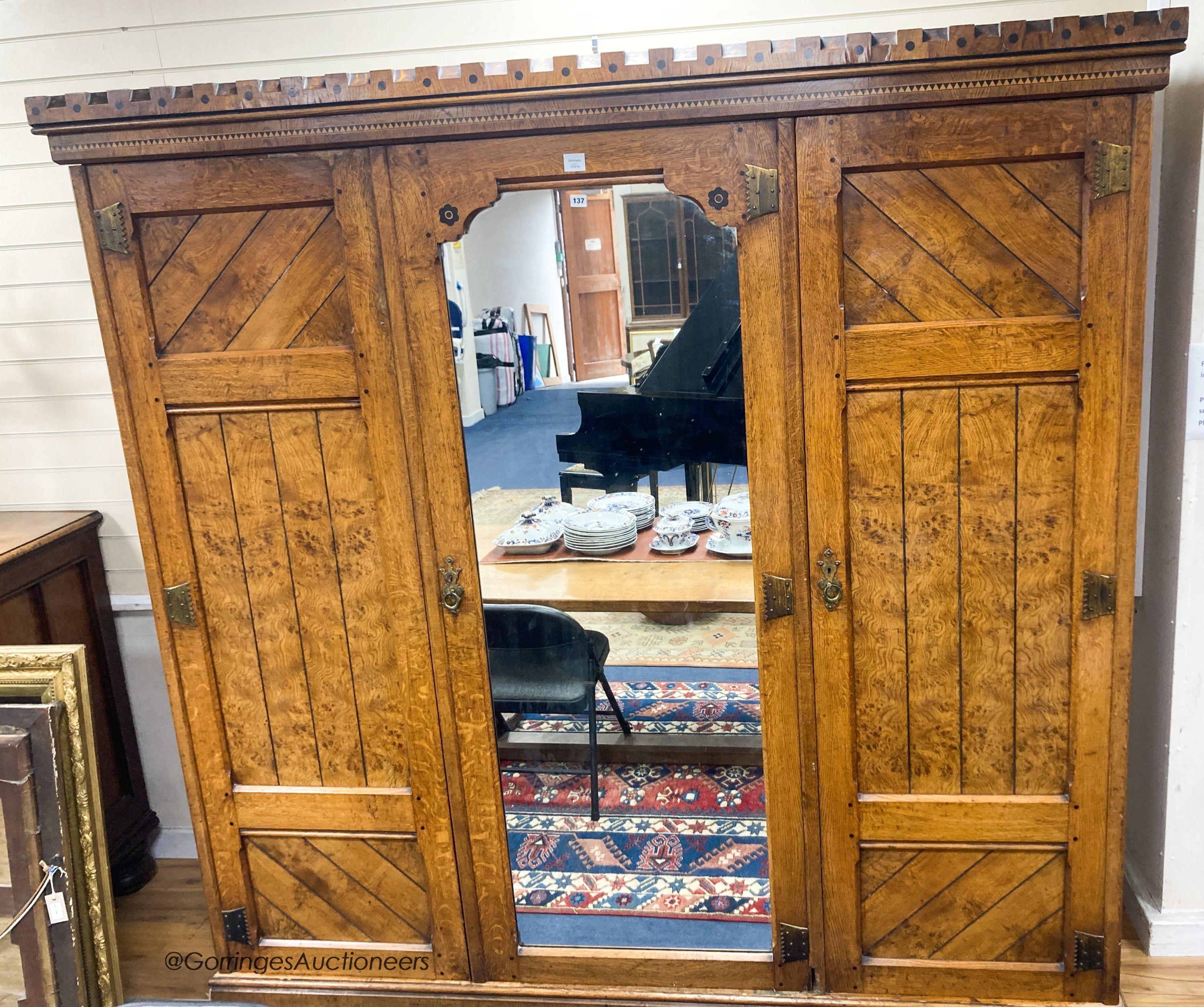 A late Victorian inlaid oak and pollard oak Aesthetic movement three door mirrored wardrobe by Garnett & Son, Warrington, length 216cm, depth 64cm, height 213cm